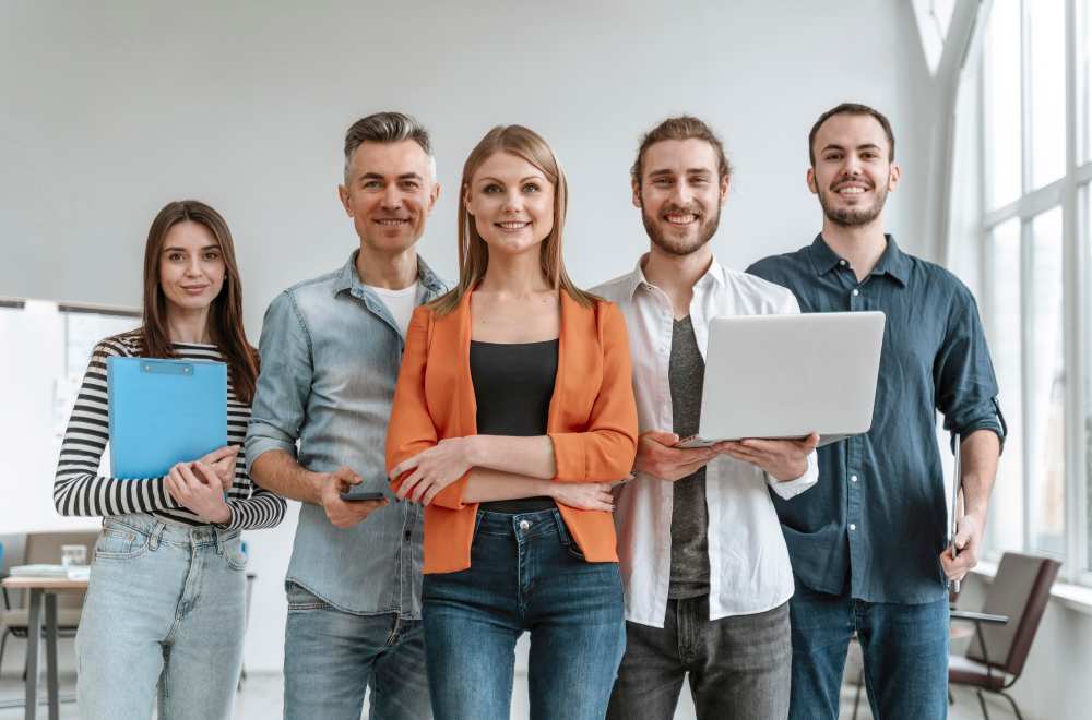 Five employees with laptops and folders, showcasing examples of employee advocacy in the workplace.